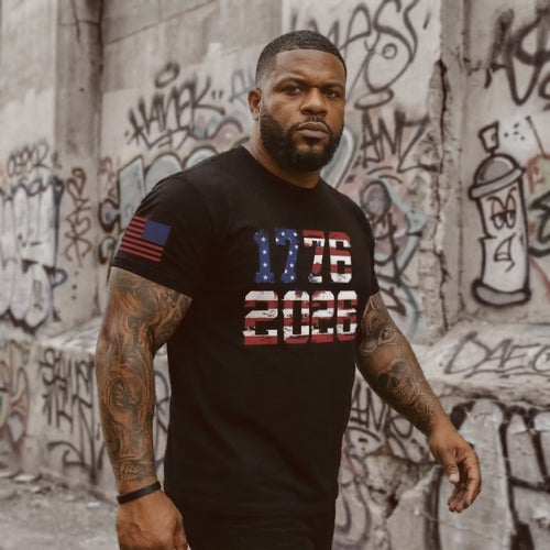 Man wearing black 1776 2026 American flag patriotic t-shirt walking in urban street setting