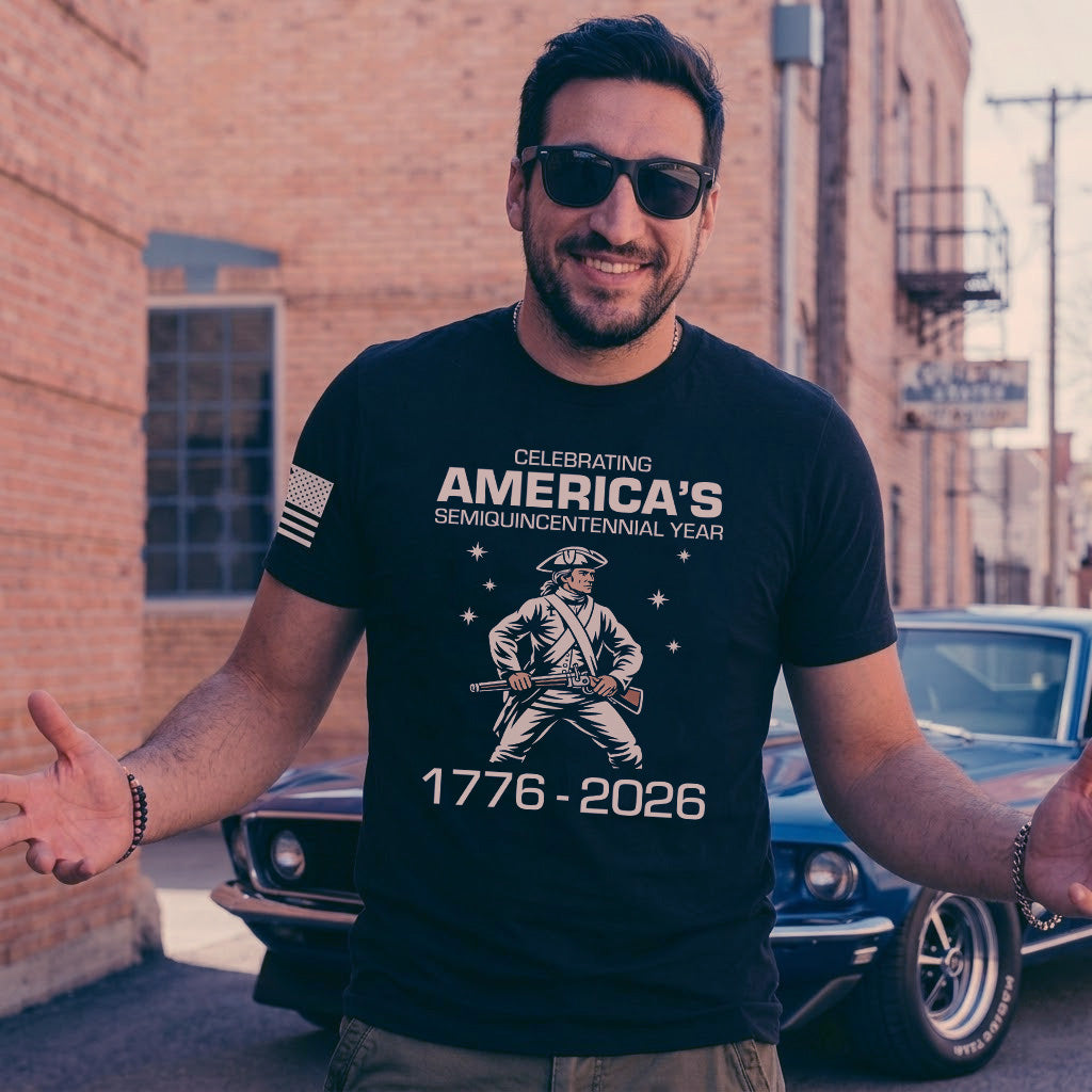 Man wearing black America semiquincentennial 1776 2026 patriotic t-shirt smiling outdoors near classic car